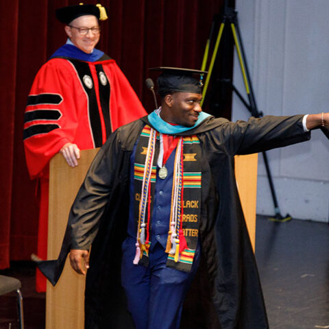 Graduate on stage pointing out to the crowd