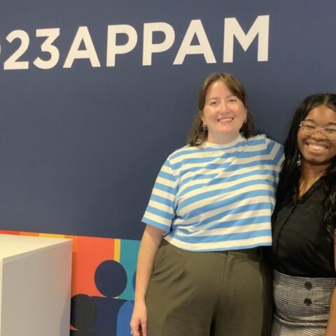 Two PhD students standing in front of APPAM sign