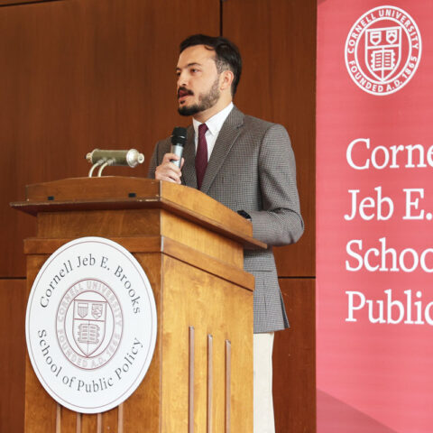 MPA student standing at podium with red Brooks School banner behind them