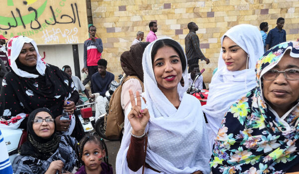 Activist in Sudan wearing white giving the peace sign to the camera