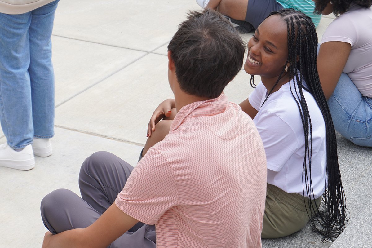 Two students sitting outside talking and smiling