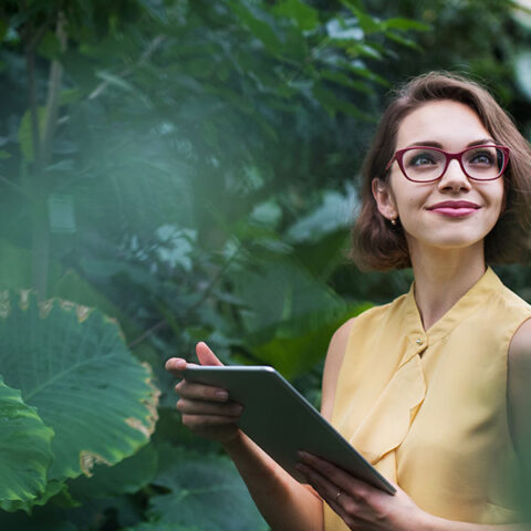 Woman working in botanic garden surrounded by plants