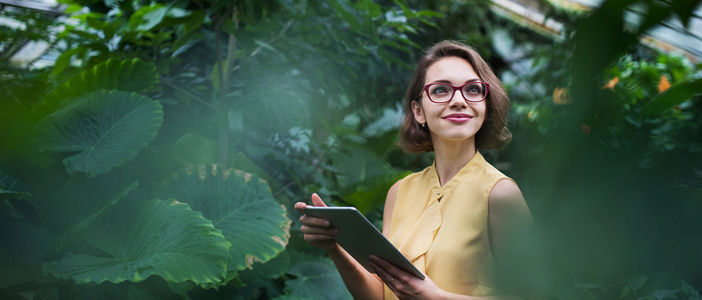 Woman working in botanic garden surrounded by plants
