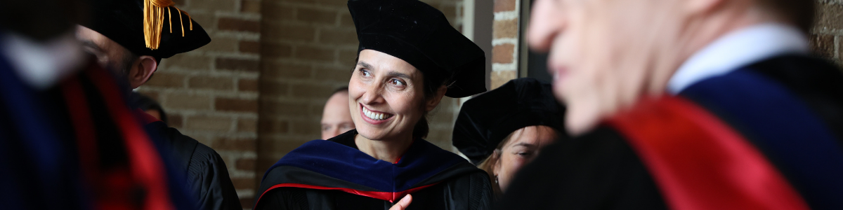 Professor in cap and gown clapping during graduation