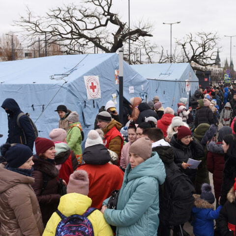 Group of refugees standing outside medic tents