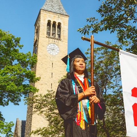 Cornell clock tower in with a Brooks graduate walking in front of it