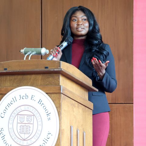Sloan student presenting at podium with reads Cornell Brooks School