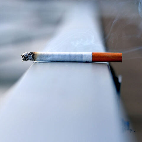 Lit cigarette balancing on a railing