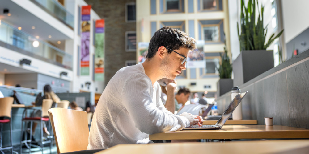 Student typing on laptop in Duffield Hall Atrium