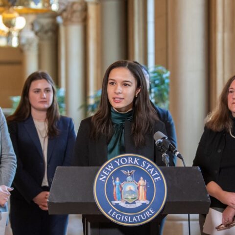 Student standing in front of podium with NY State seal
